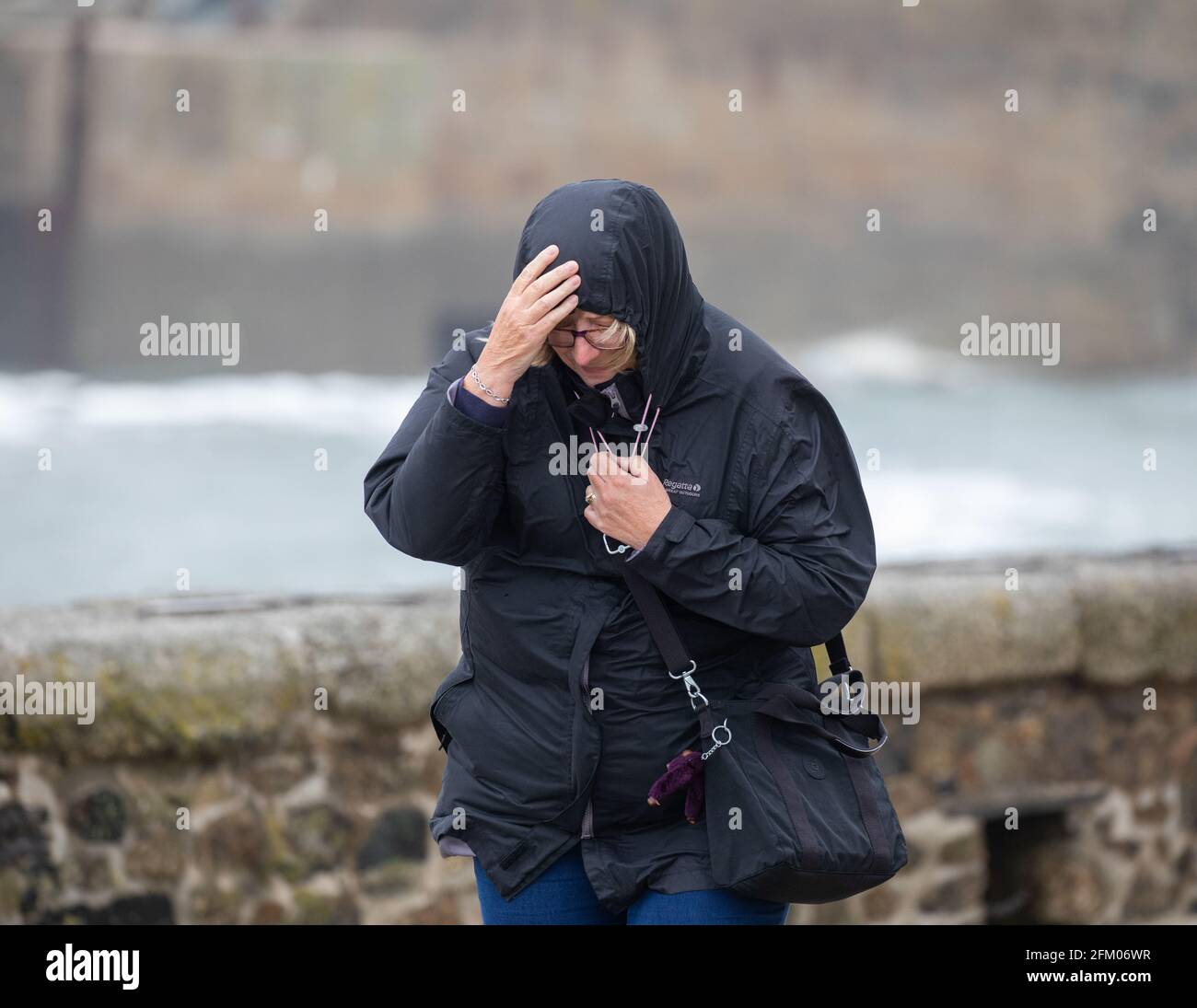 La gente lotta per camminare contro i venti forti in Porthleven, Cornovaglia, Regno Unito Foto Stock