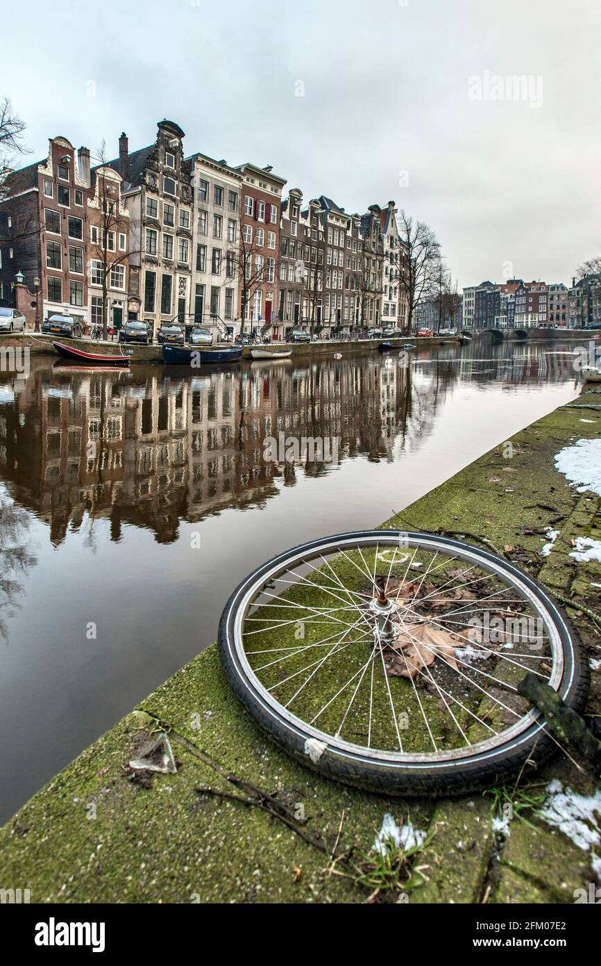 Ruota ciclabile sul bordo del canale con edifici storici sullo sfondo, Amsterdam, Olanda del Nord, Paesi Bassi Foto Stock