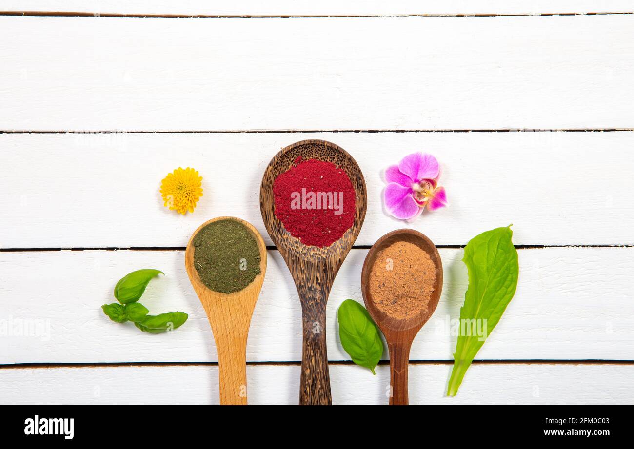 Lotto di cucchiai di legno con polvere di supercibo in una fila su sfondo bianco minimo del bordo di legno con molto spazio di copia. Foto Stock