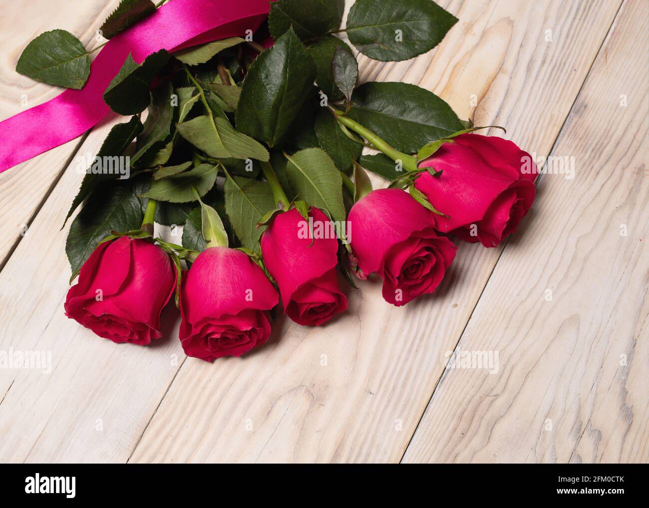 Bouquet di rose rosso scuro su sfondo tavola di legno. Composizione del fiore di saluto. Un regalo piacevole e romantico per il tesoro. Foto Stock