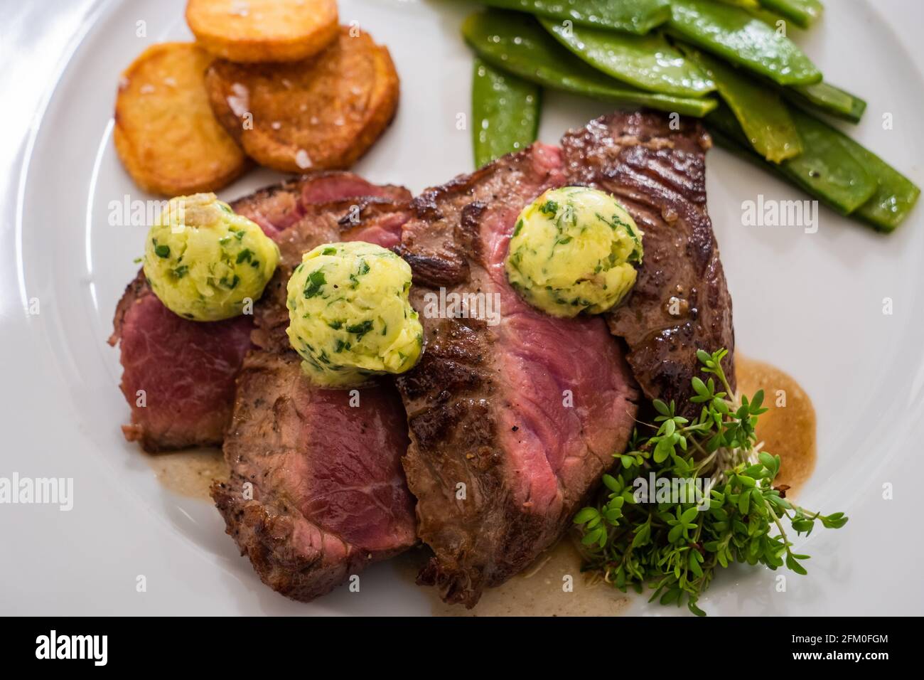 Entrecote con burro di erbe e crescione, potatos di Pomme Souffle e fagioli verdi Foto Stock