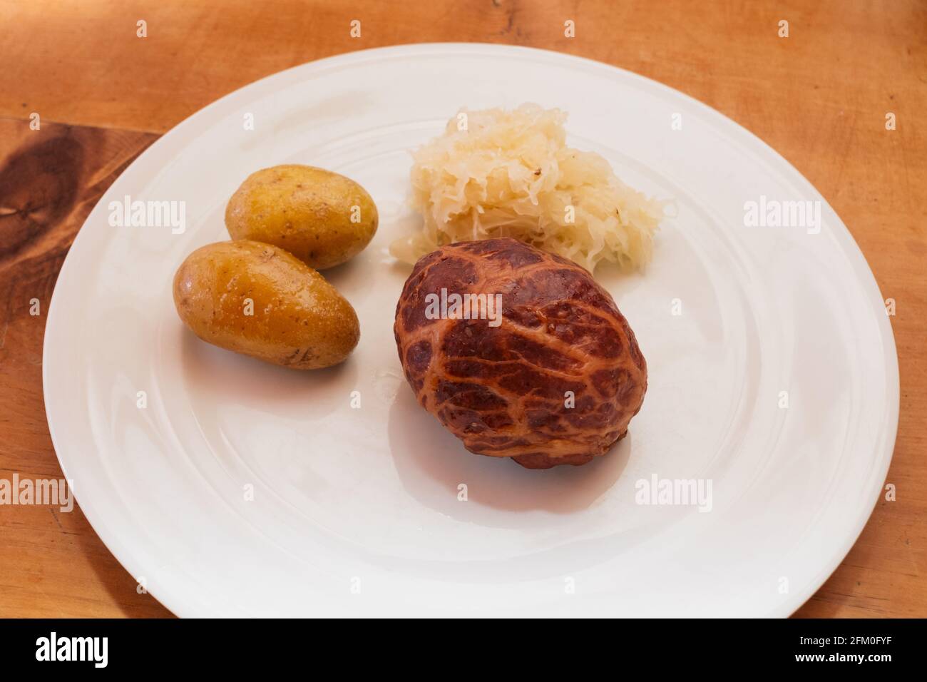 Saumaise, un maul di maiale ripieno di carne stagionata, con Sauerkraut e nuovi potatos su un piatto bianco, un piatto tradizionale della bassa Austria Foto Stock