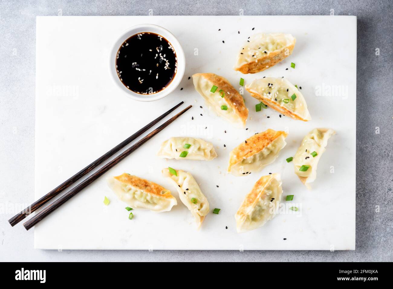 Giaozi, Gyoza, gnocchi cinesi fritti serviti con salsa di soia su una tavola di marmo bianco. Vista dall'alto Foto Stock