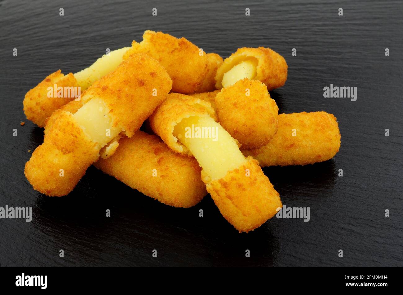 Gruppo di grattugiate di mozzarella ricoperte di pane su un'ardesia sfondo di pietra Foto Stock