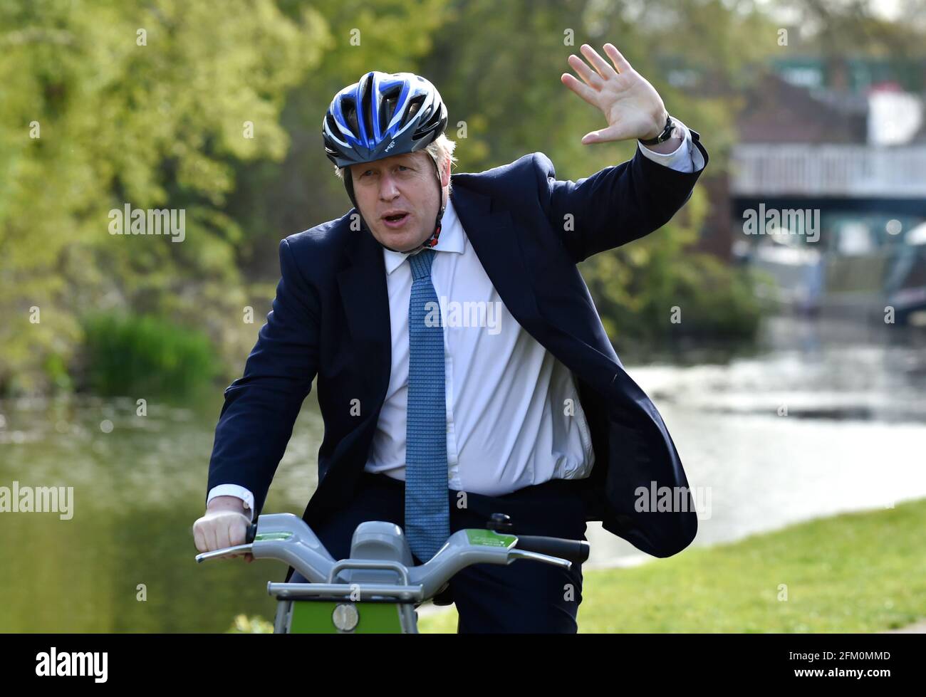 Il primo ministro Boris Johnson si fa ondeggiare mentre fa un giro in bicicletta lungo l'alzaia del canale di Stourbridge nelle West Midlands, mentre si trova sulla pista elettorale locale. Data immagine: Mercoledì 5 maggio 2021. Foto Stock