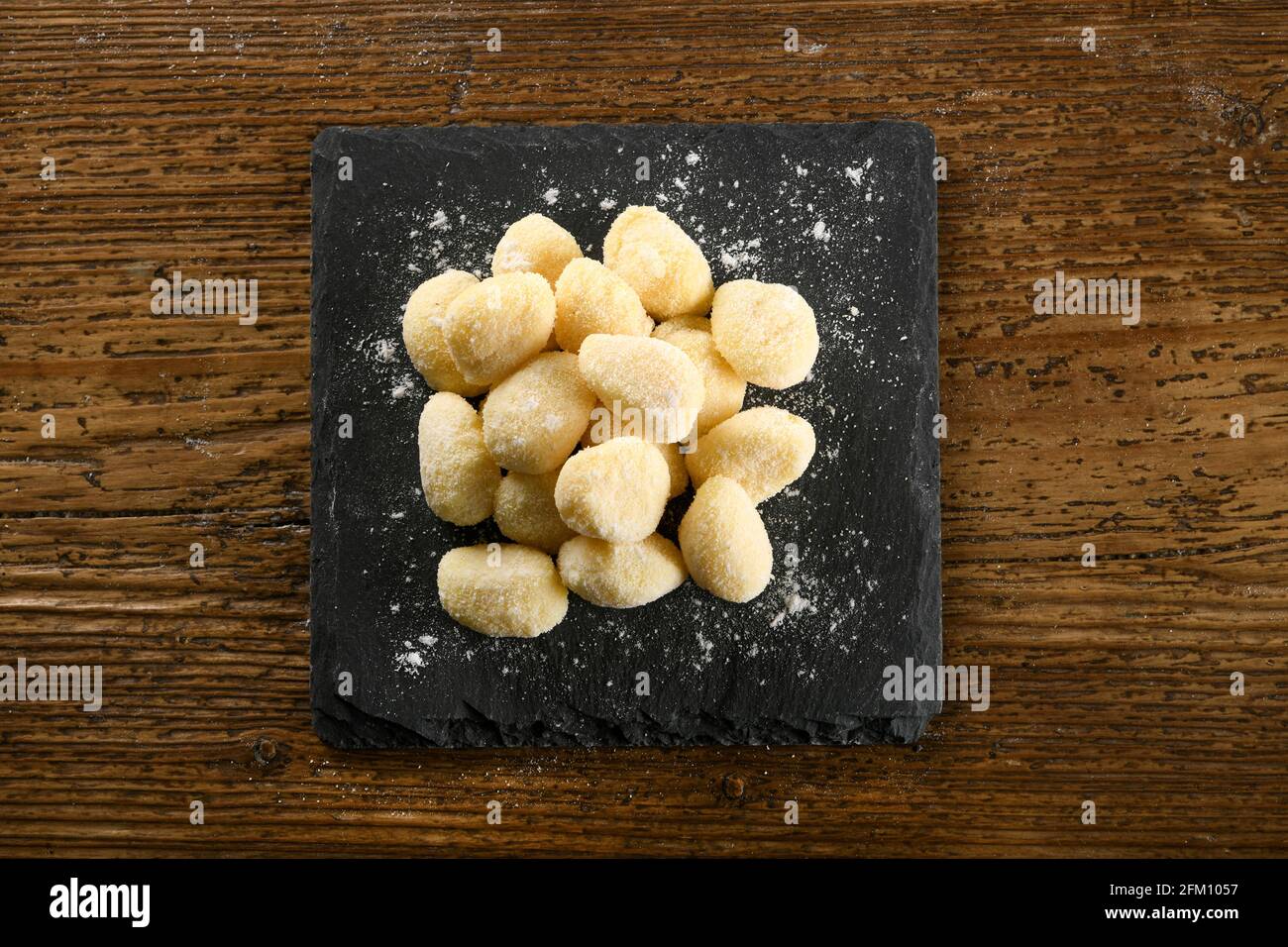 Vista dall'alto della pasta di gnocchi italiani non cotti a bordo su tavola di legname Foto Stock