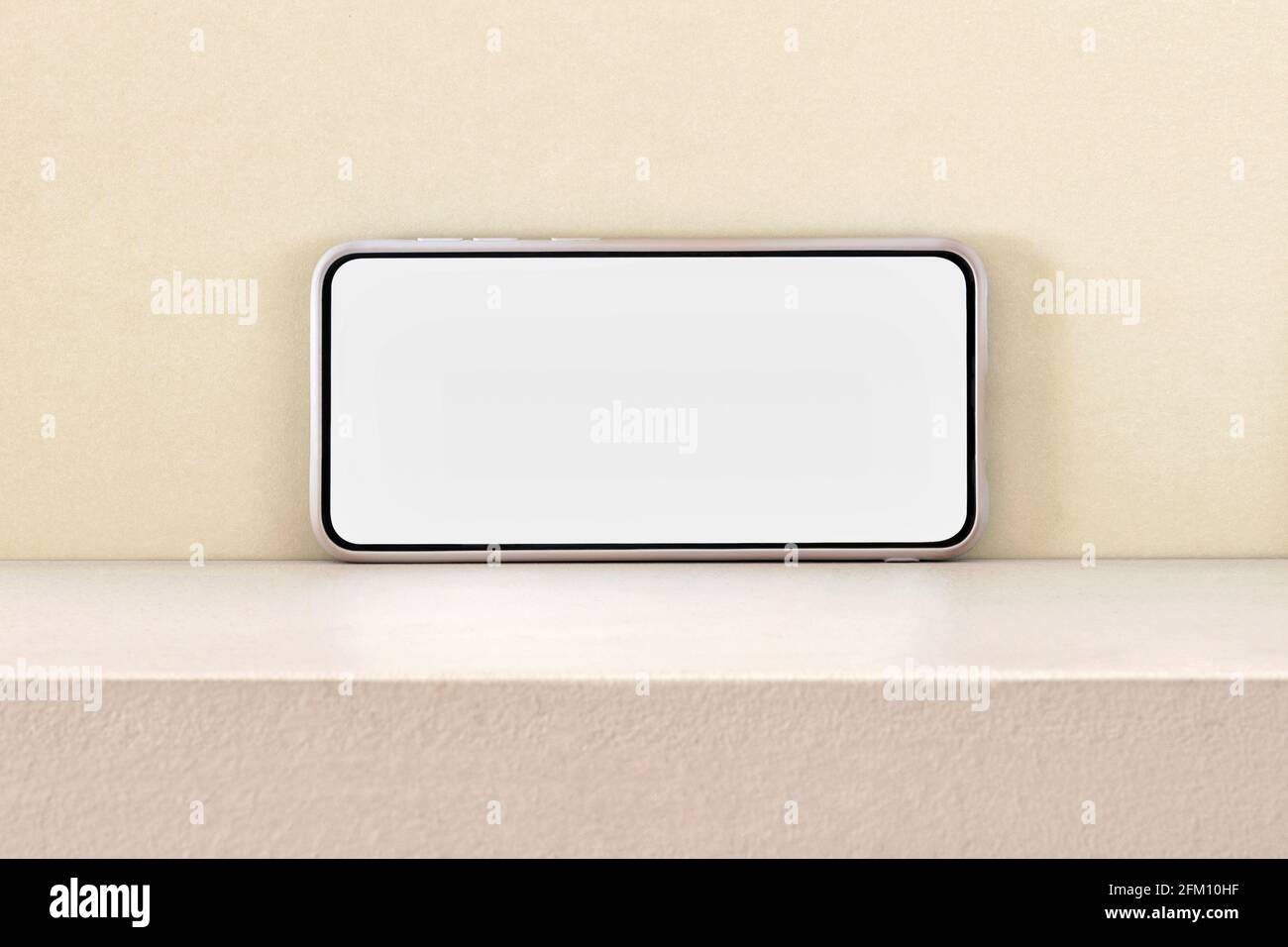Telefono cellulare moderno con schermo vuoto per i dati inseriti ripiano contro parete giallo chiaro Foto Stock