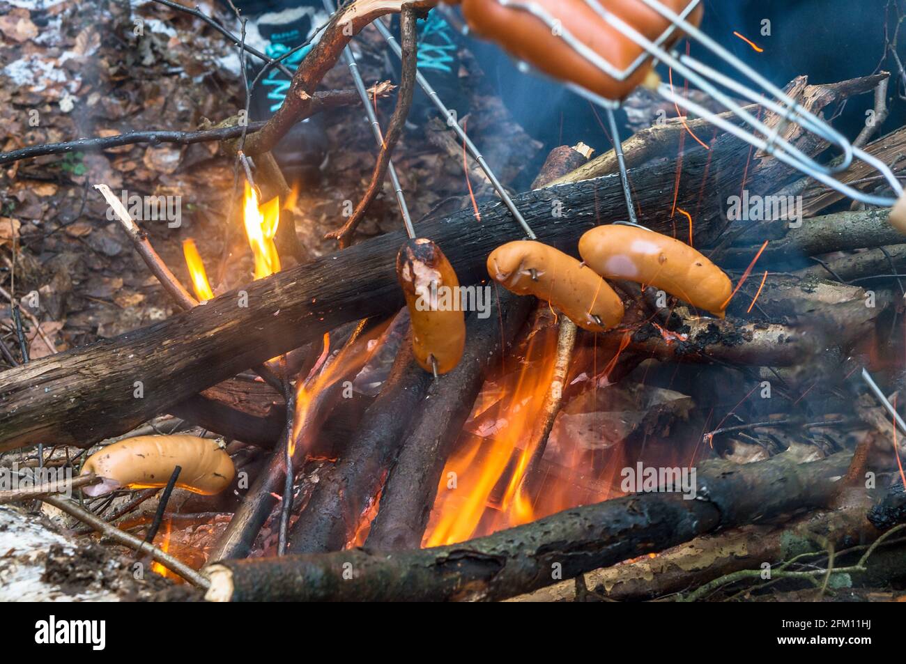 Salsiccia arrosto sul fuoco. Cucina sopra un falò. Torrefati sul fuoco. Foto Stock