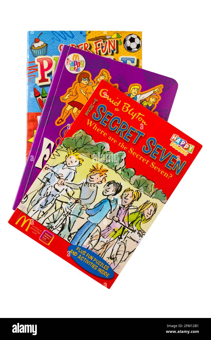 Mucchio di libri per bambini con il libro Enid Blyton Secret Seven In cima isolato su sfondo bianco - McDonalds pasto felice prenota Foto Stock