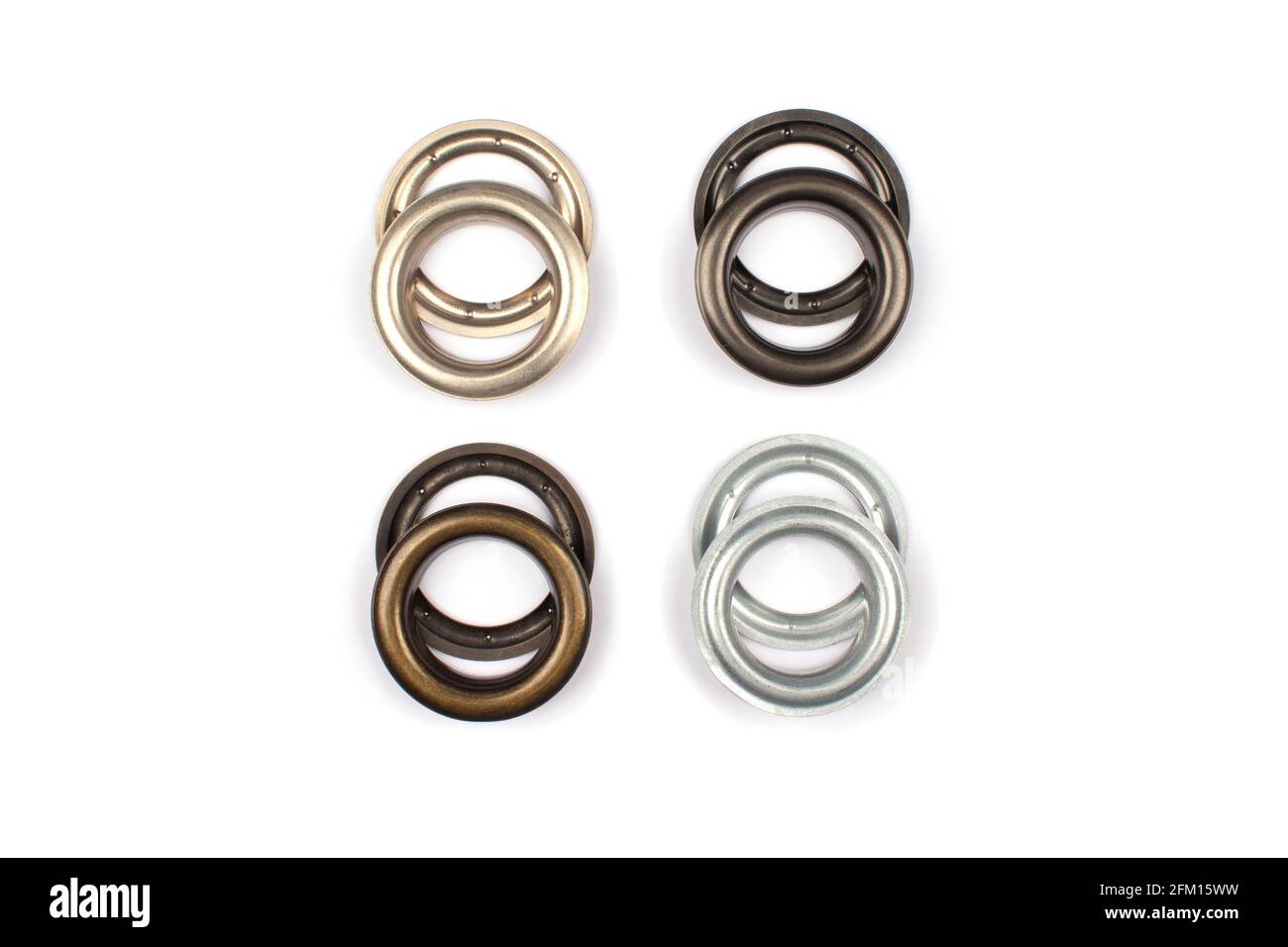 Diversi occhielli o rivetti metallici multicolore in ottone - tendine anelli per il fissaggio del tessuto al cornice, isolati su sfondo bianco con Foto Stock