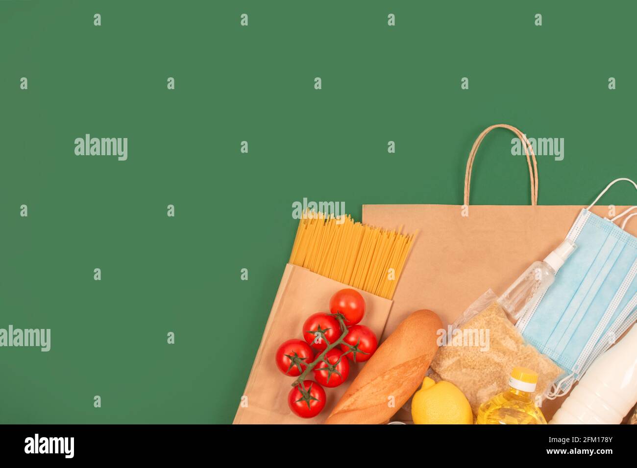 Donazioni di cibo e medicinali e sacchetto di carta su sfondo verde con spazio per la copia: Pasta, verdure, cibo in scatola, baguette, olio da cucina. Banca di cibo Foto Stock