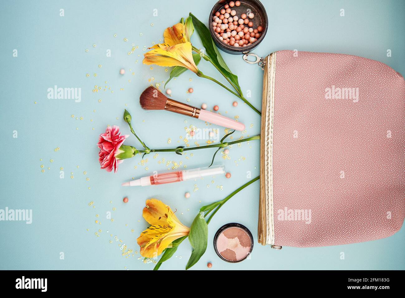 Esplosione di accessori cosmetici per il trucco dalla frizione rosa. Pennelli per trucco, polvere, creare ombre e fiori. Foto di alta qualità Foto Stock