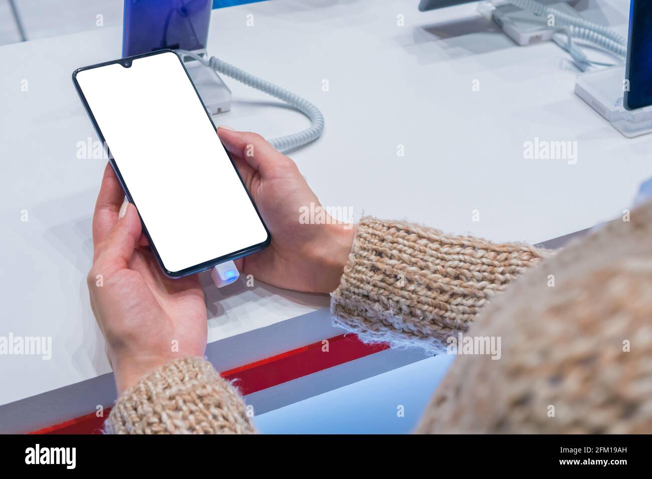 Mock up: donna guardando smartphone con schermata bianca vuota in un negozio, negozio Foto Stock