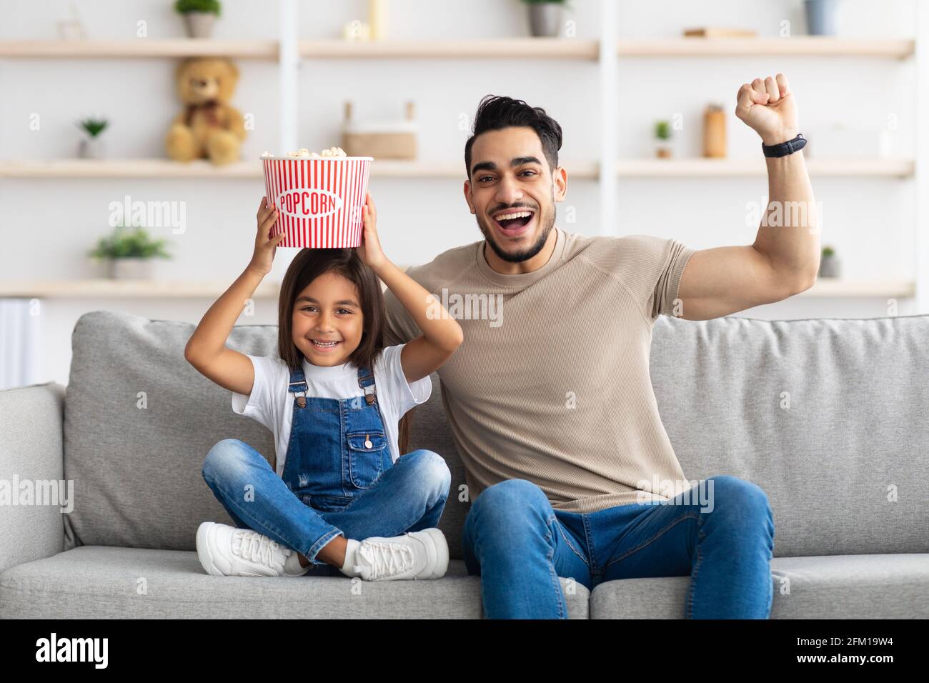 Felice giovane famiglia che guarda la televisione seduto sul divano Foto Stock