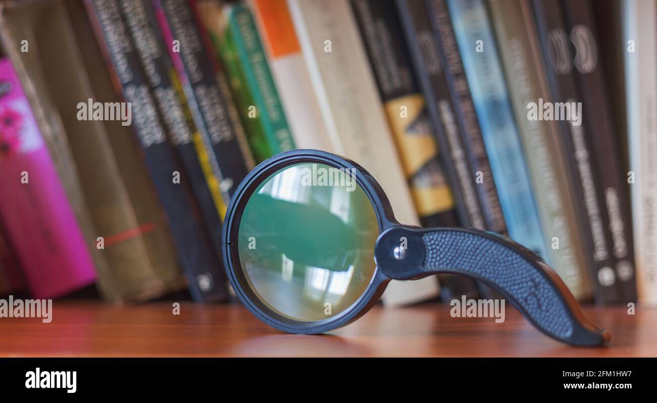 Lente di ingrandimento su una libreria, sfondo con libri Foto Stock
