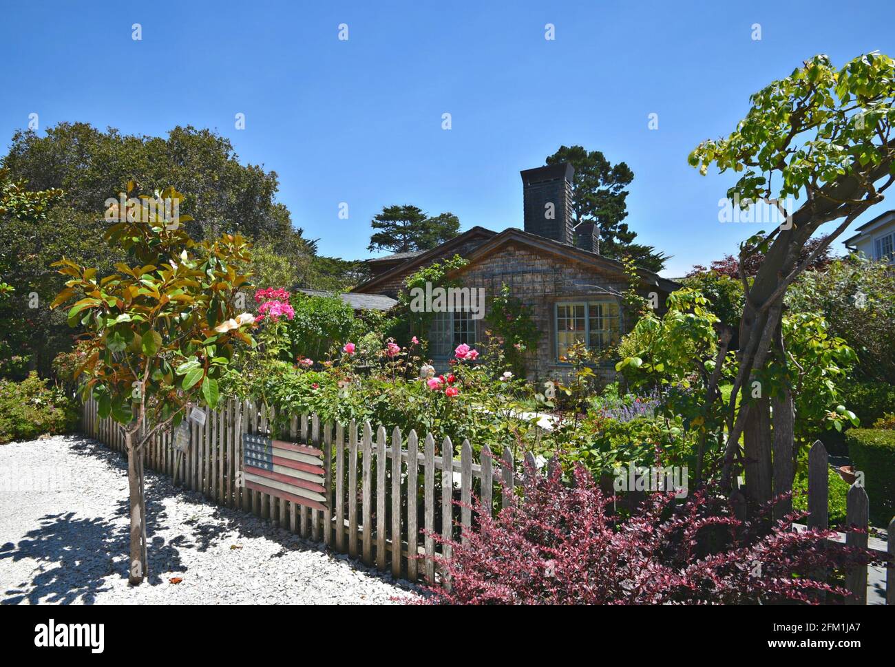 Paesaggio con un cottage fiaba circondato da cipressi e un giardino tropicale da sogno alla periferia di Carmel-by-the-Sea in California, Stati Uniti. Foto Stock