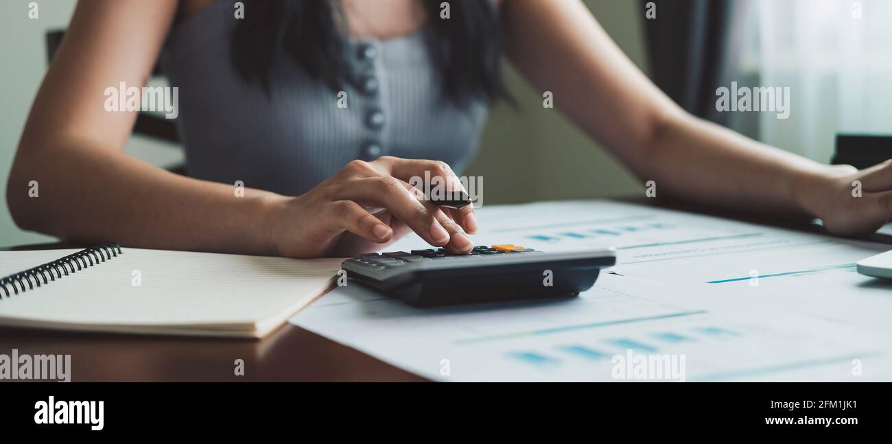 Donna d'affari che lavora in finanza e contabilità analizza il budget finanziario con calcolatrice a casa Foto Stock