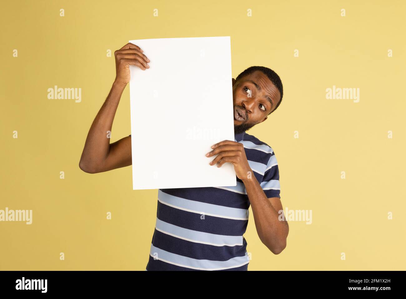 Uomo africano felice con foglio bianco di carta isolato sopra sfondo giallo studio Foto Stock