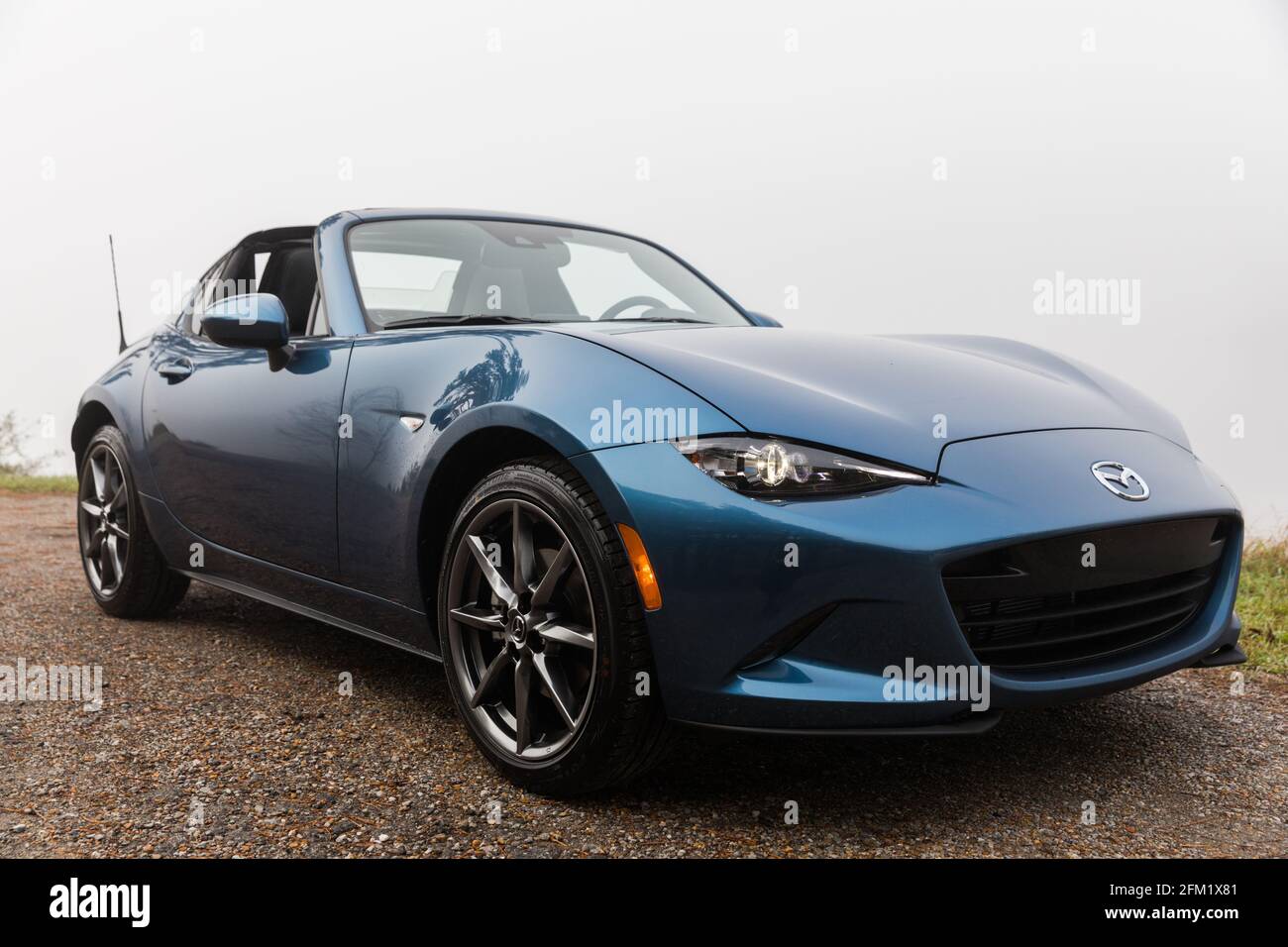 Nuovo blu 2020 Mazda MX-5 GT RF, parcheggiato (con il tetto in giù) accanto all'acqua in una mattina foggy. Foto Stock