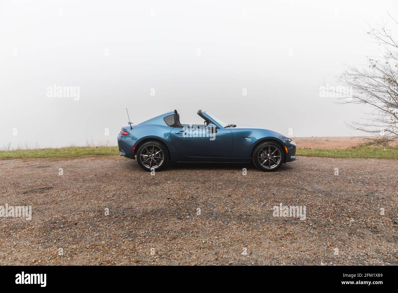 Nuovo blu 2020 Mazda MX-5 GT RF, parcheggiato (con il tetto in giù) accanto all'acqua in una mattina foggy. Foto Stock