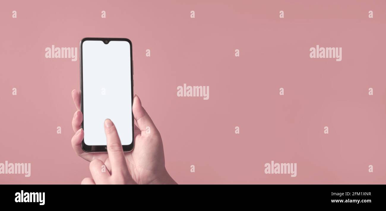 Smartphone femminile con schermo vuoto su sfondo rosa. Mokup del telefono. Foto Stock