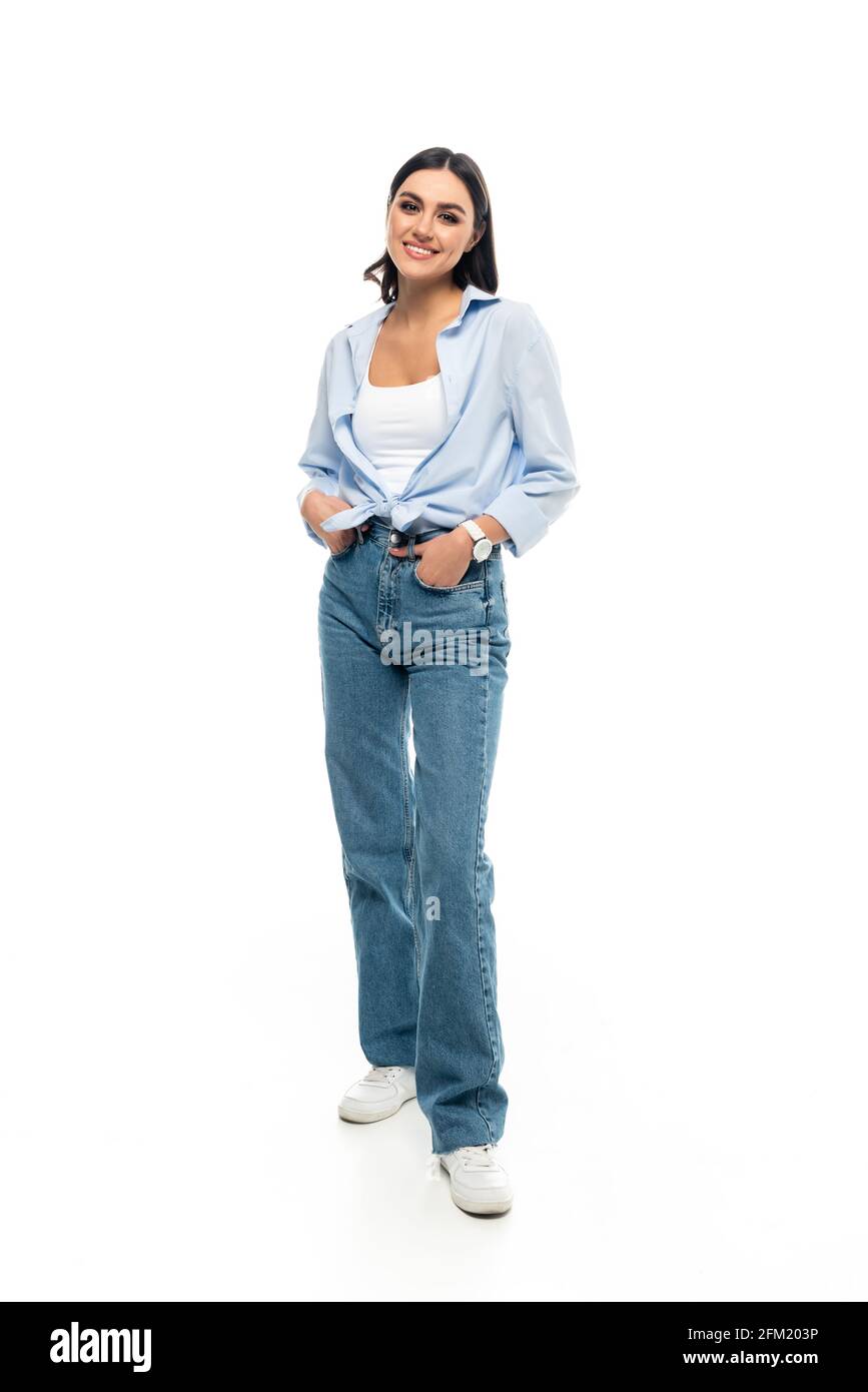 vista completa di una donna elegante in piedi con le mani in mano tasche di jeans su sfondo bianco Foto Stock