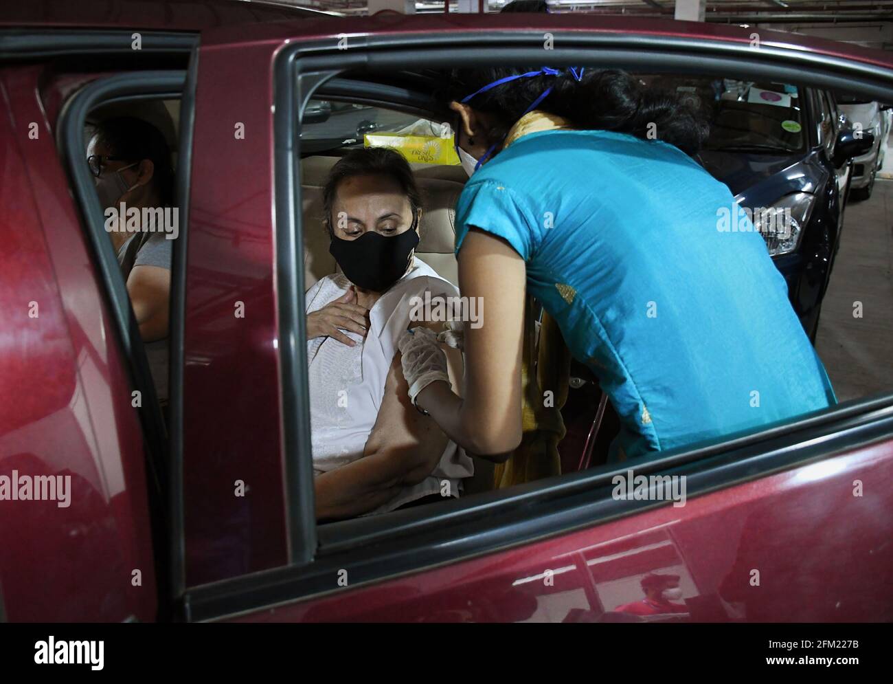 Mumbai, India. 05 maggio 2021. Un operatore sanitario che indossa una maschera facciale somministra una dose di vaccino COVID19 ad una donna all'interno della sua auto al parcheggio pubblico Kohinoor a Mumbai. Questa struttura è aperta per soddisfare gli anziani e le persone diversamente abili. (Foto di Ashish Vaishnav/SOPA Images/Sipa USA) Credit: Sipa USA/Alamy Live News Foto Stock