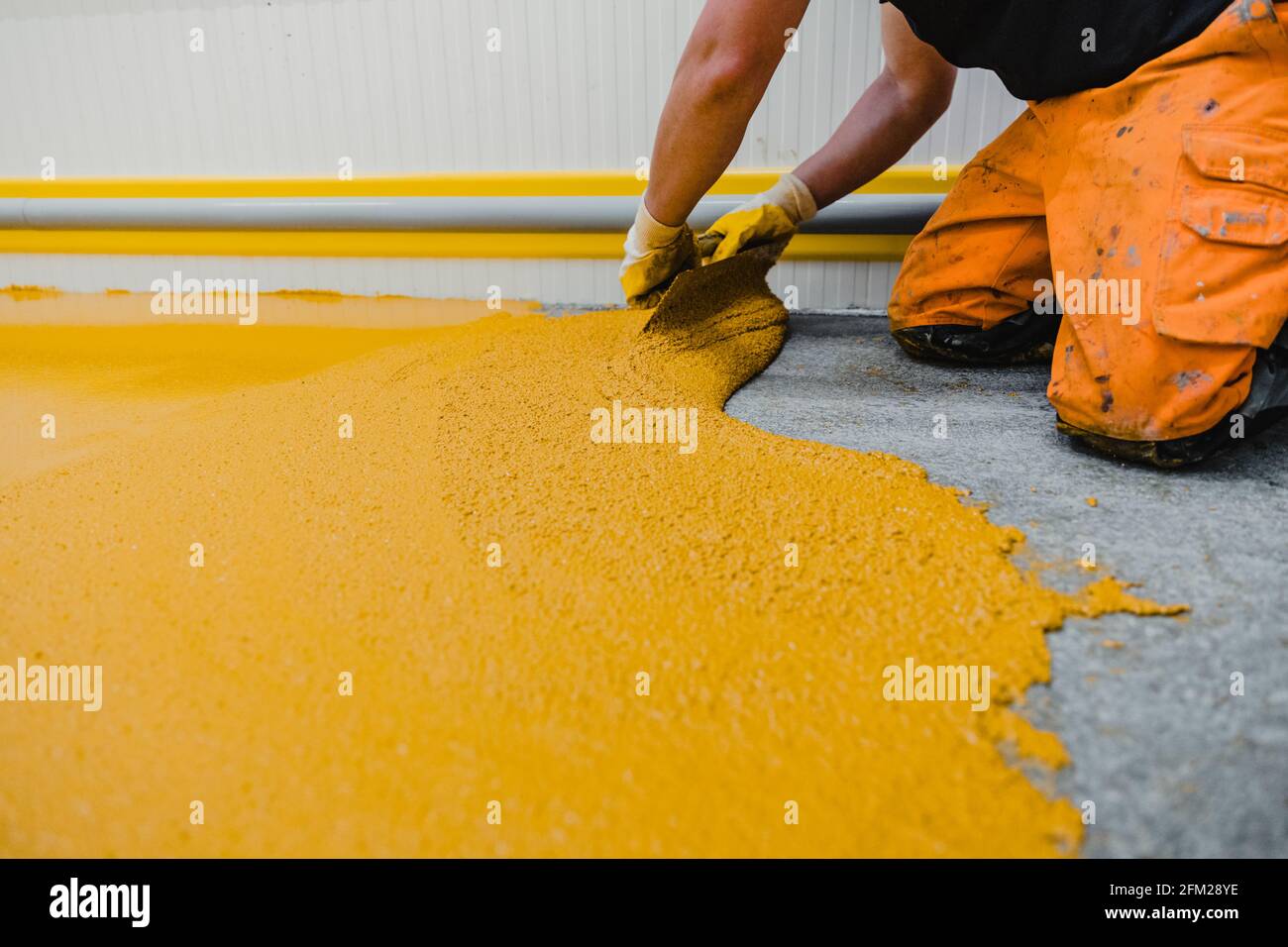 Lavoratore che applica pavimenti in resina epossidica e poliuretanica system.These prodotti facili da pulire hanno anche caratteristiche antiscivolo. Foto Stock