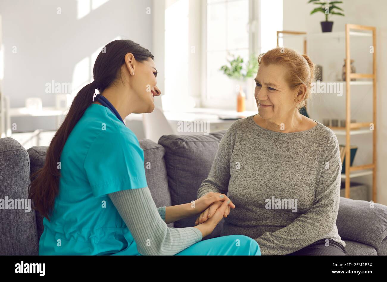 La paziente anziana femminile e l'operatore sanitario hanno una bella conversazione in infermieristica reparto di casa Foto Stock