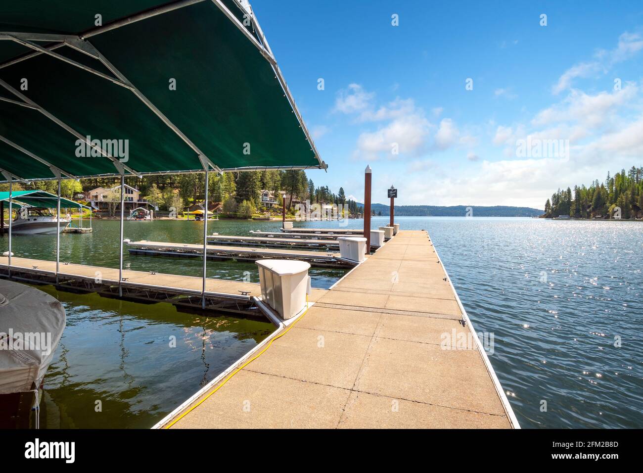 Una passerella con scivoli in barca al porticciolo di Rockford Bay, con case sul lungomare in lontananza a Coeur d'Alene, Idaho, USA Foto Stock