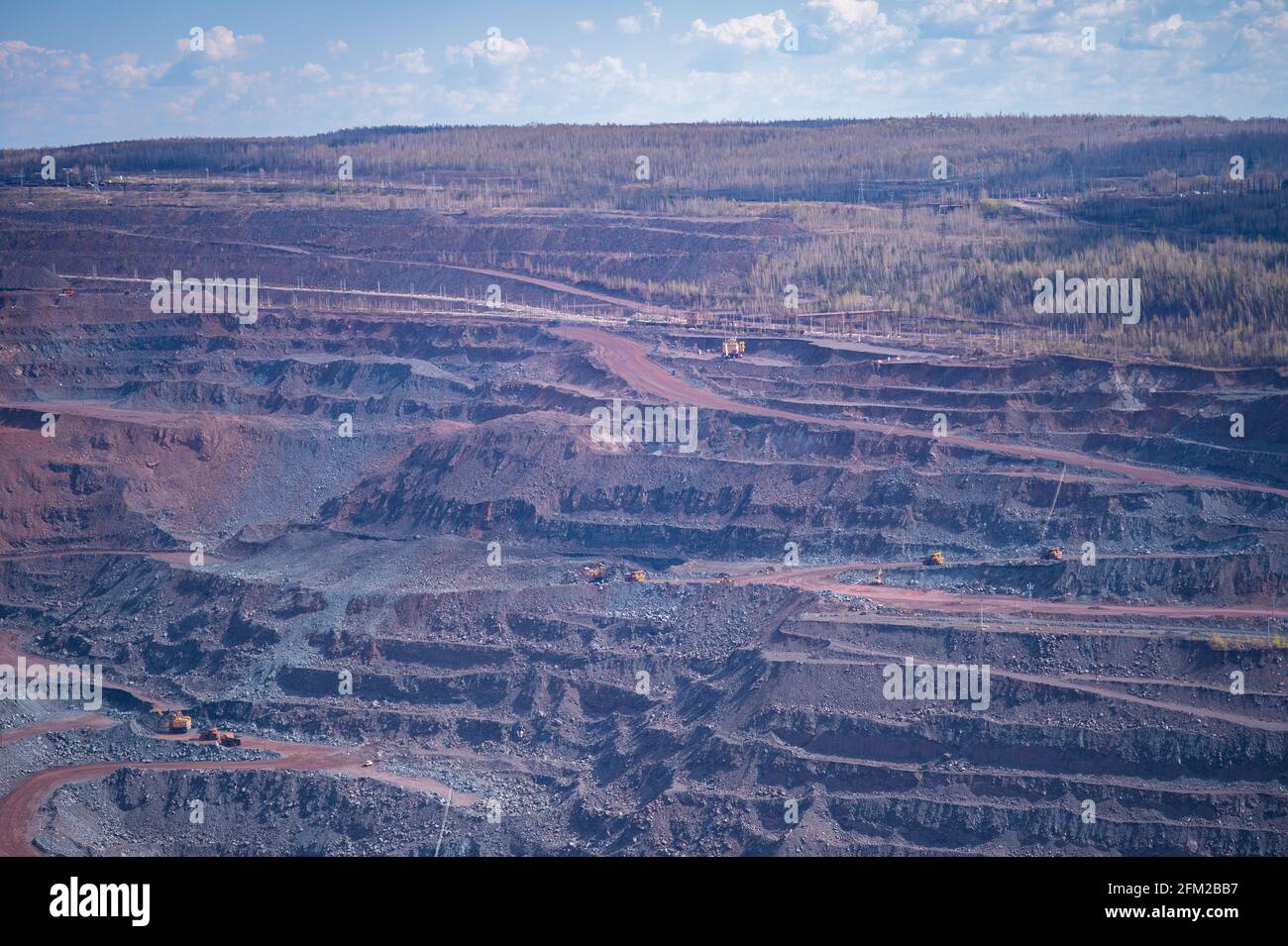 Vista di una parte di una cava di minerale di ferro con varie sfumature di quarzite rosa e blu e terrazze per la rimozione di minerale. Sfondo. Copiare lo spazio. Foto Stock