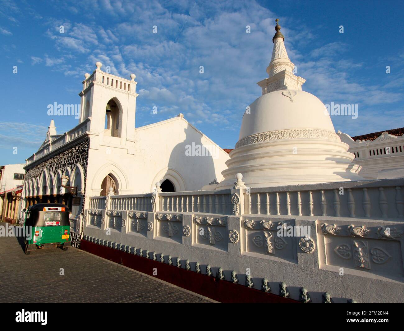 Il famoso e distintivo complesso del Tempio Buddista Sri Sudharmalaya bianco con un tuk tuk verde all'alba in una mattina limpida e blu. A Galle, Sri Lanka. Foto Stock