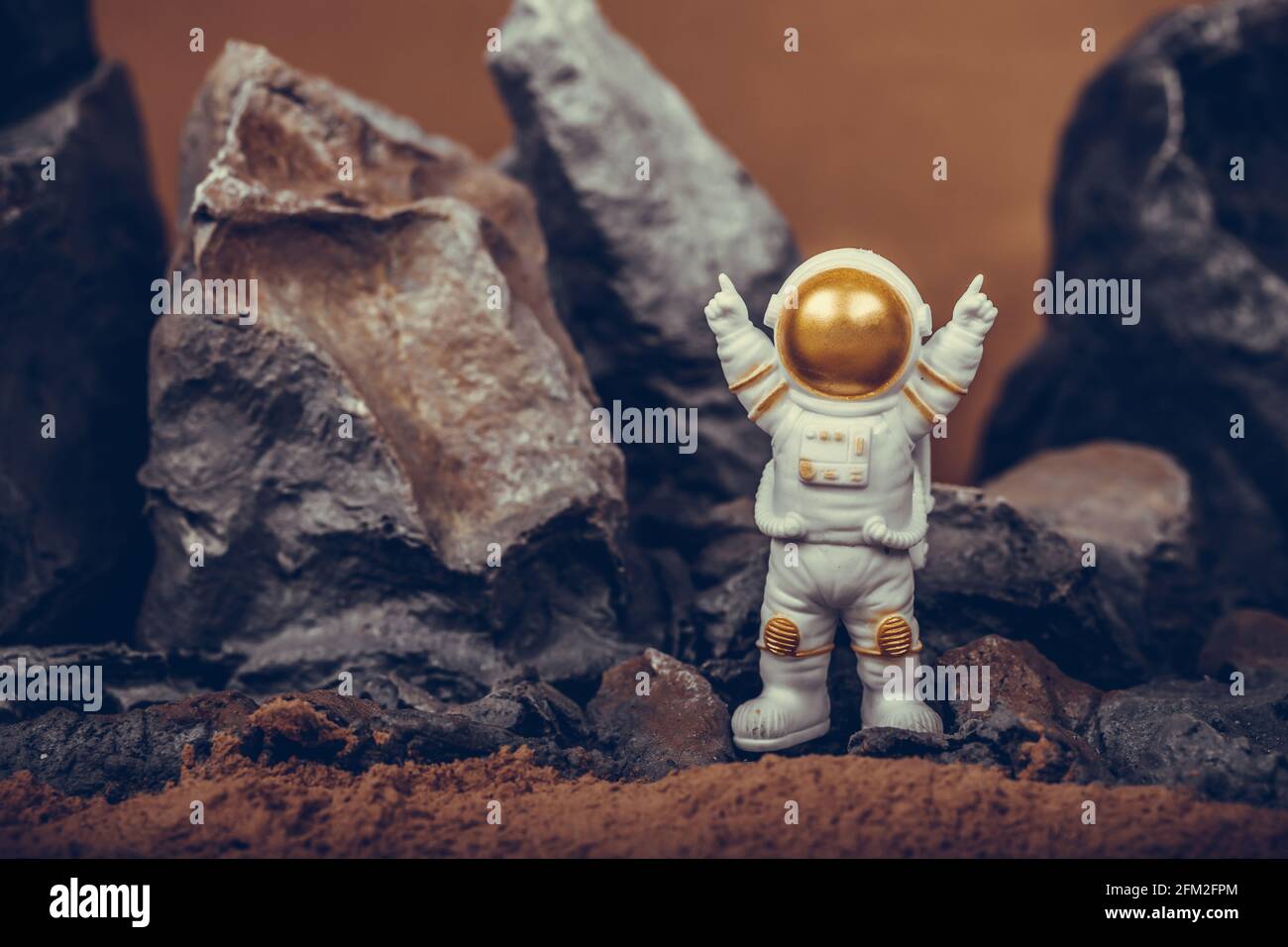 Astronauta alzando le braccia mentre si trova su una montagna rocciosa. Spaceman indossa tuta spaziale bianca e casco. Concetto di cosmonautica, di spazio, di libertà Foto Stock