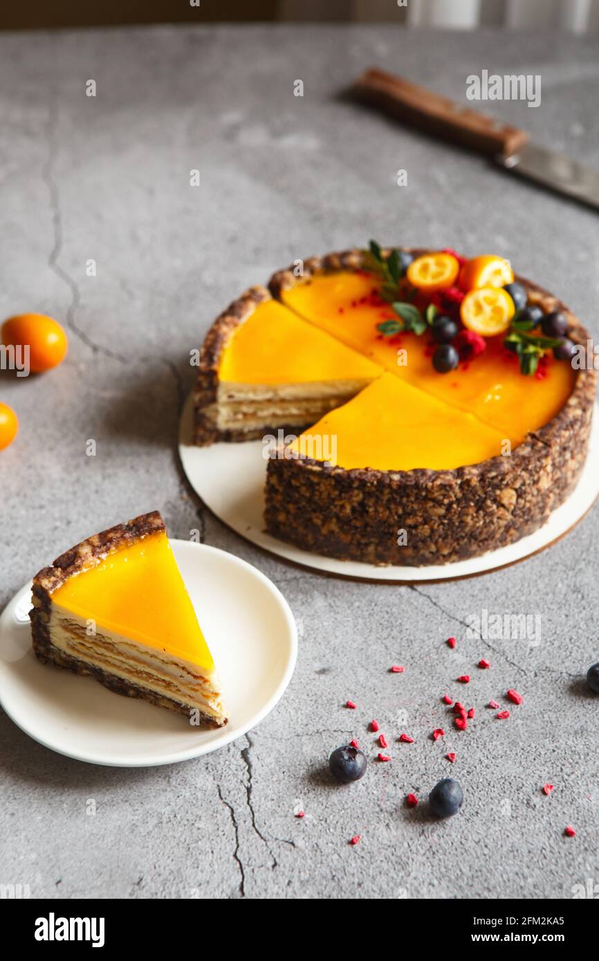 Torta al formaggio con frutta di mango su sfondo grigio. Torta al formaggio con salsa alla frutta a passione, decorata con frutti di bosco e frutta Foto Stock