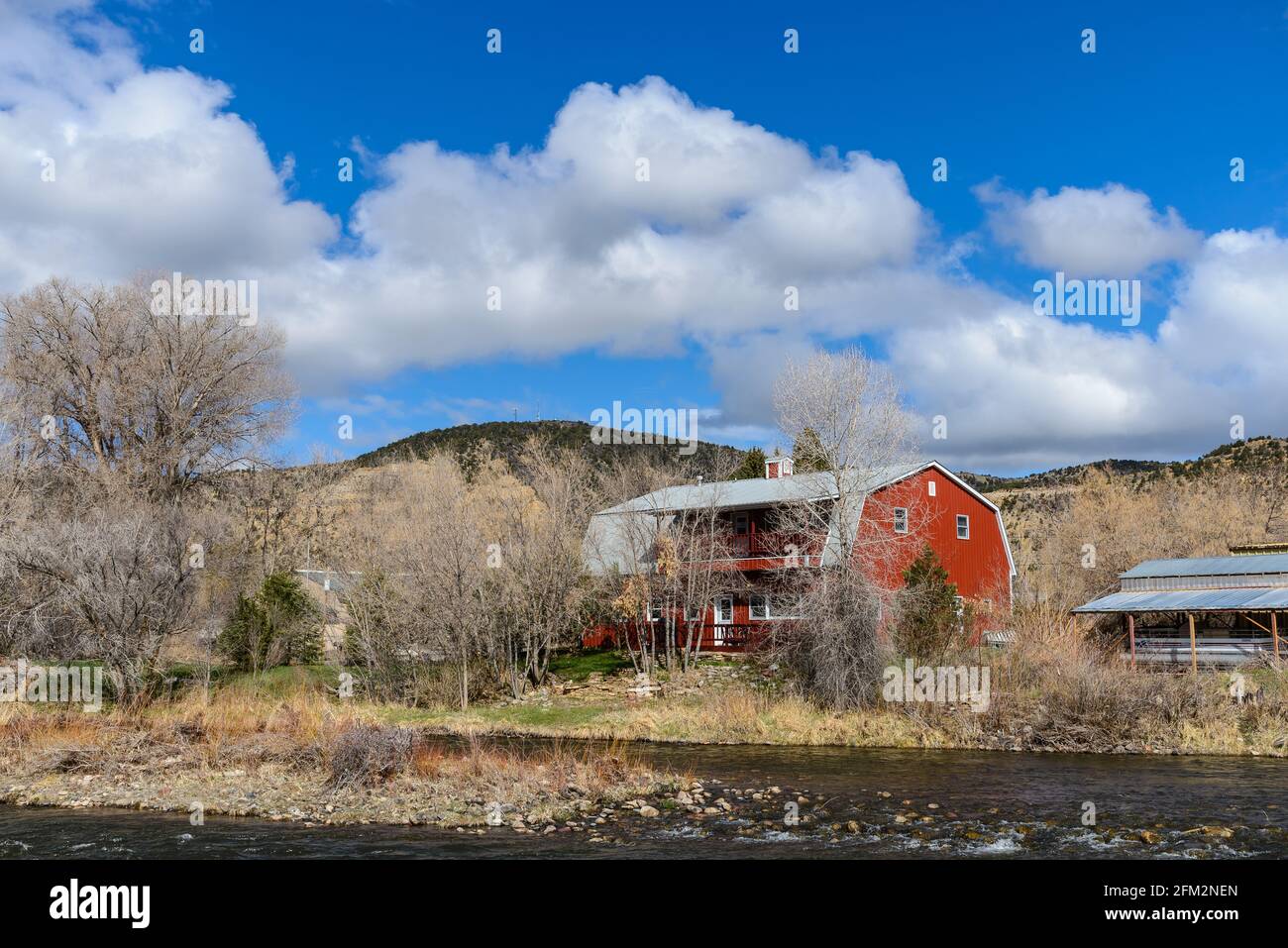 Una casa in stile granaio rosso vicino ad un fiume. Colorado, Stati Uniti. Foto Stock