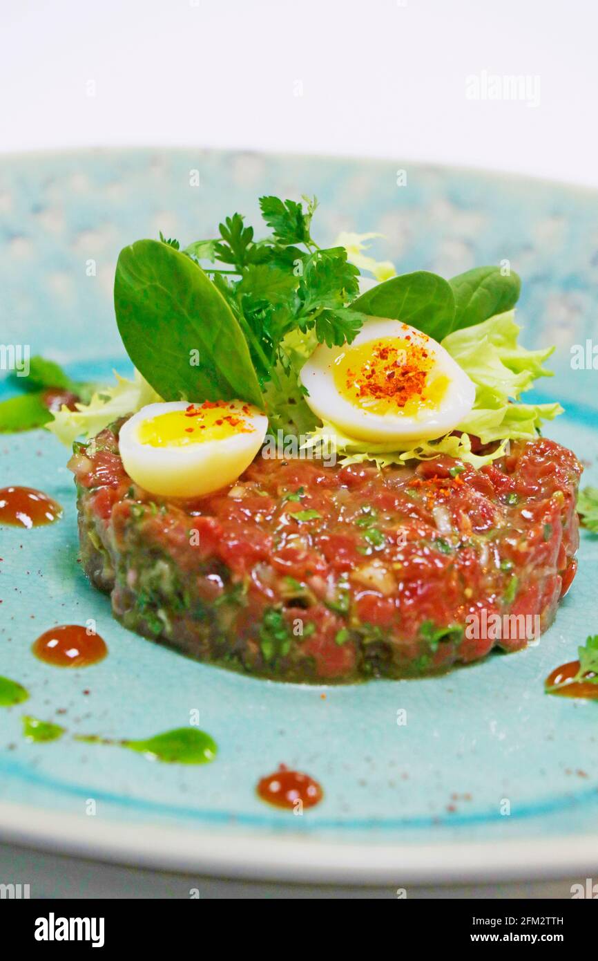 specialità crude food, tartare di manzo o tartare di bistecca con foglie e uova Foto Stock