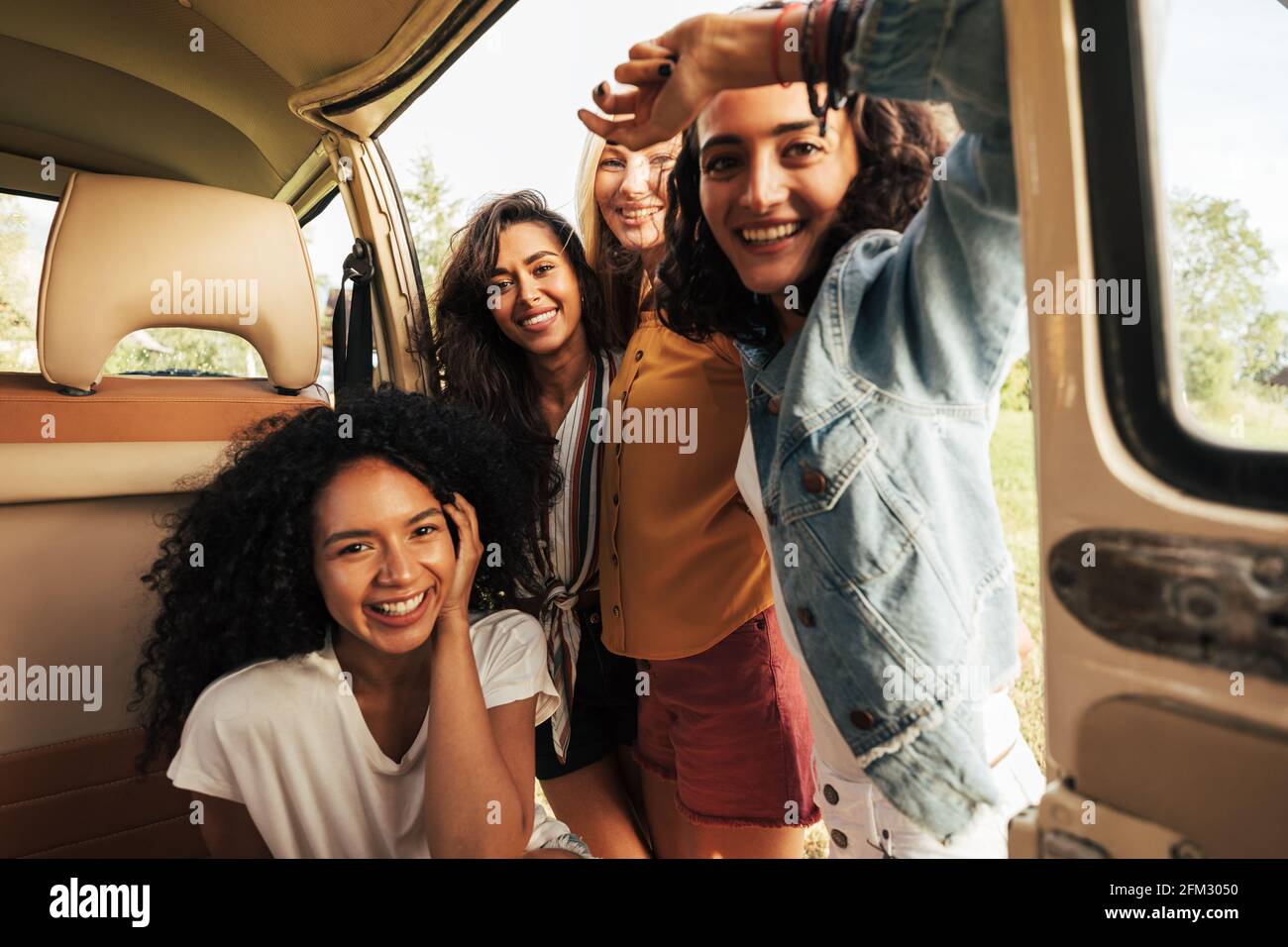 Quattro belle donne che guardano la macchina fotografica mentre si siede in minivan Foto Stock