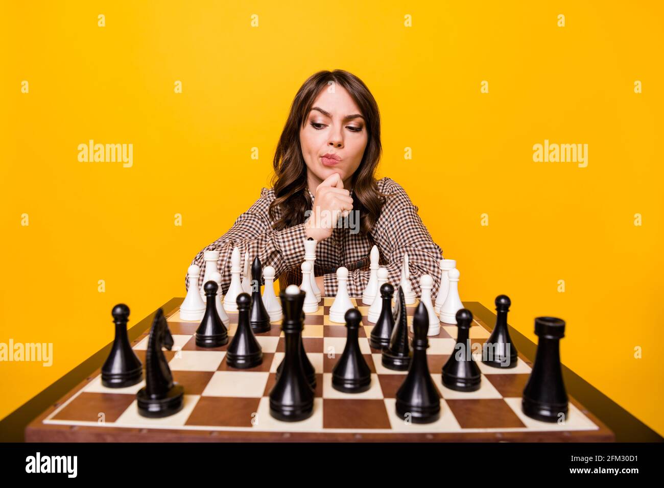 Foto di una bella bruna signora siede gioco di scacchi mano camicetta di  usura del mento isolata su sfondo di colore giallo vivo Foto stock - Alamy