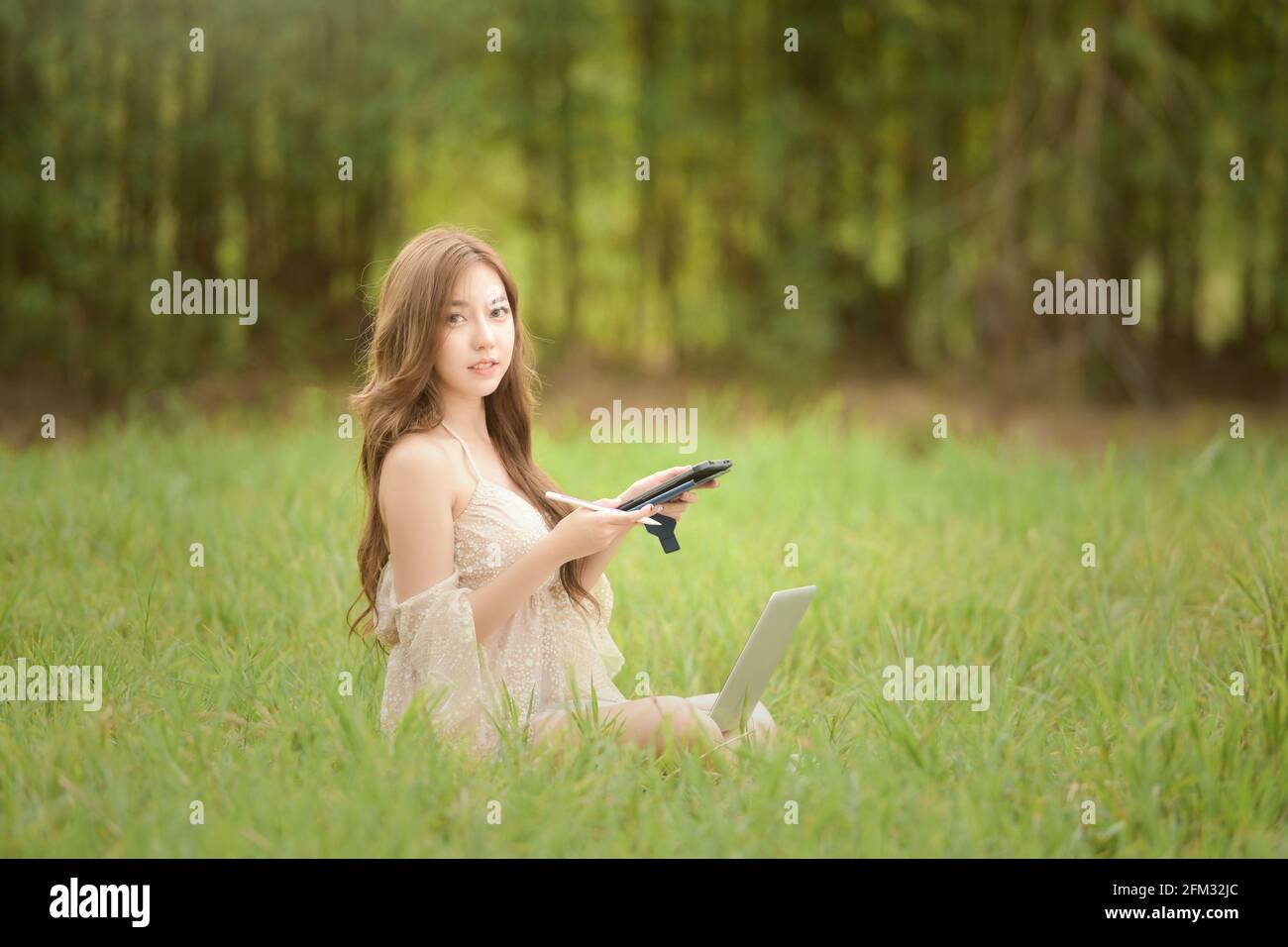 Bella donna seduta in un prato che lavora in estate, Thailandia Foto Stock