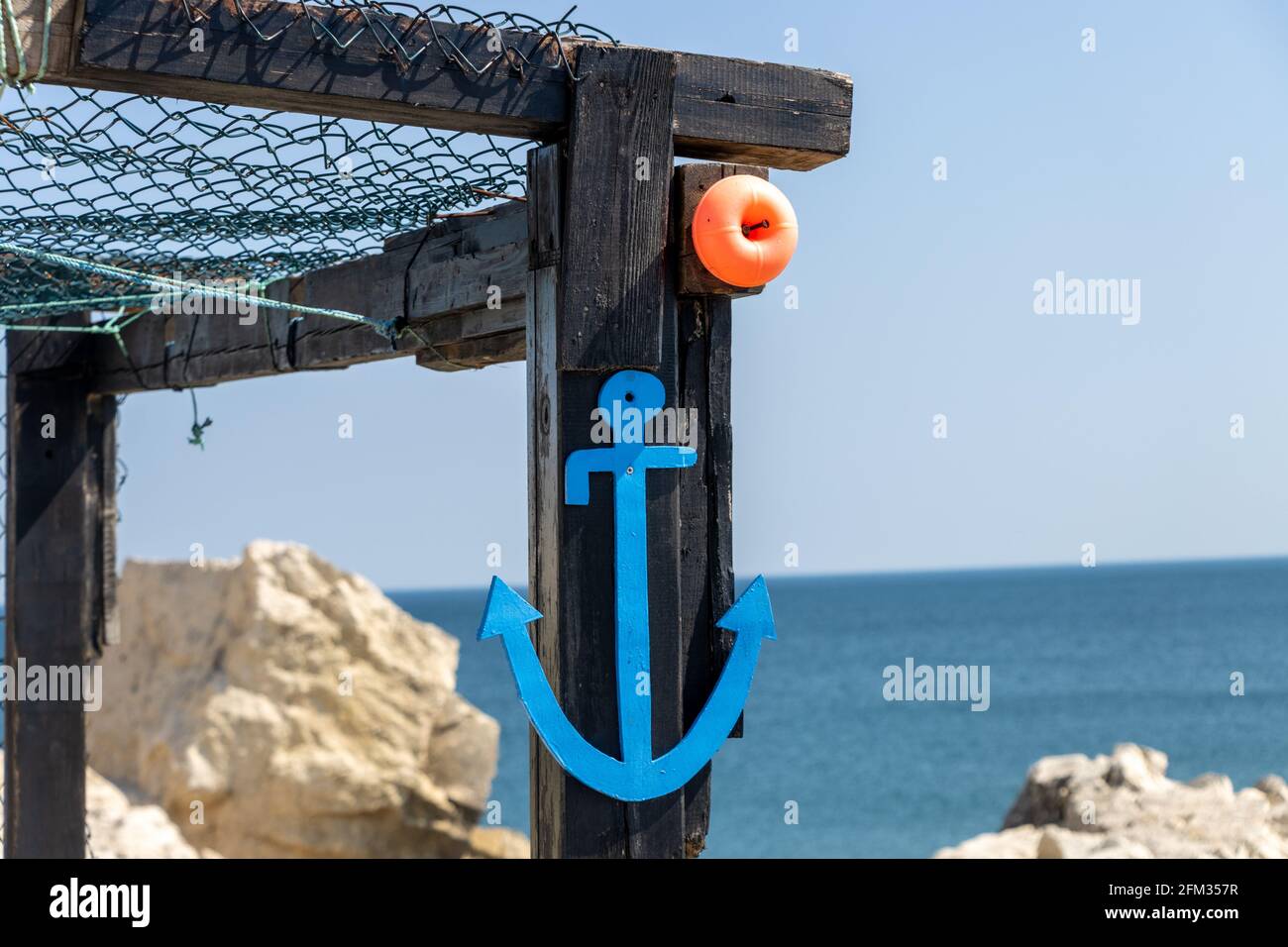 Piccola ancora blu sulla riva del mare. Mare, vacanza estiva e concetto di pesca in una giornata di sole Foto Stock