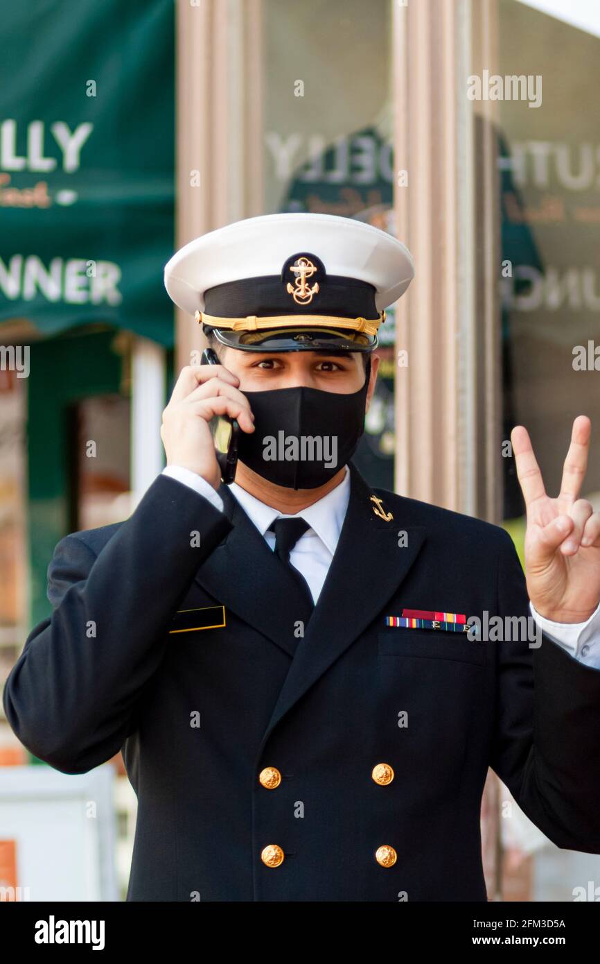 Annapolis, MD, USA 05-02-2021: Un cadetto che frequenta la US Naval Academy indossa una maschera facciale a causa della pandemia di COVID 19. Il giovane apprendista sta parlando Foto Stock