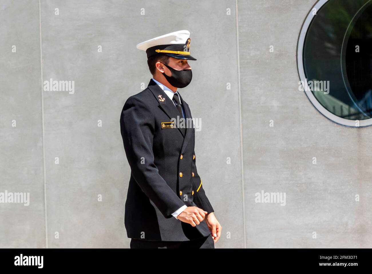 Annapolis, MD, USA 05-02-2021: Un cadetto che frequenta la US Naval Academy (USNA) indossa una maschera facciale a causa della pandemia di COVID 19. Il giovane apprendista è a piedi Foto Stock