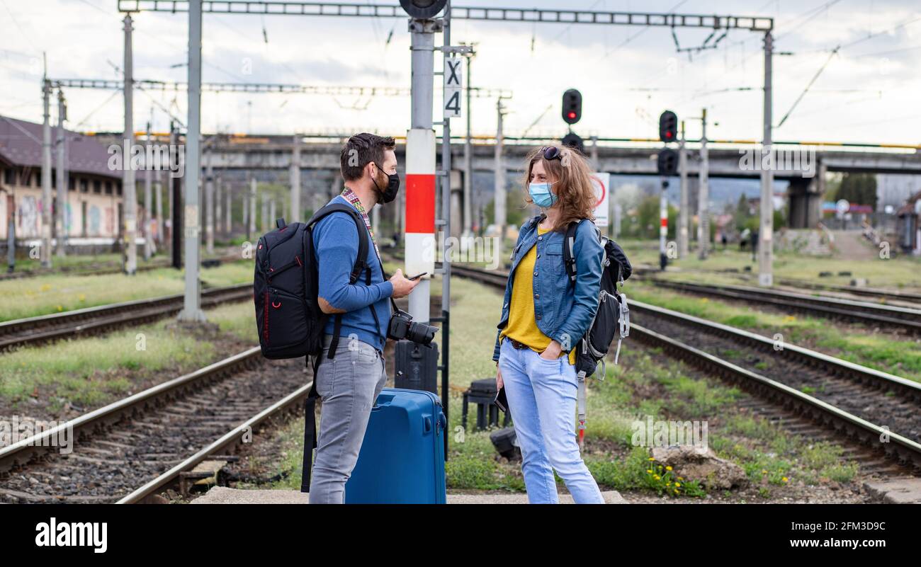 coppia che indossa la maschera nella stazione ferroviaria Foto Stock