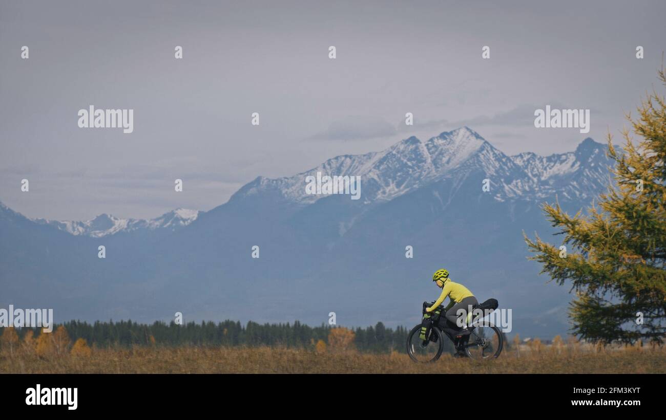 La donna viaggia in bicicletta su terreni misti con bikepacking. Il viaggio del viaggiatore con le borse della bicicletta. Sport turismo bikepacking. Foto Stock