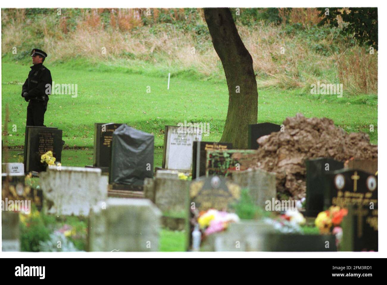 Un poliziotto a Hyde Cimitero che protegge la zona un corpo Fu esumato nelle prime ore del mattino è in piedi dietro il tumulo di terra rimosso dal Il dottor Harold Shipman è accusato di aver ucciso 15 persone I suoi paitents13.10.98 Pic:JOHN VOOS Foto Stock