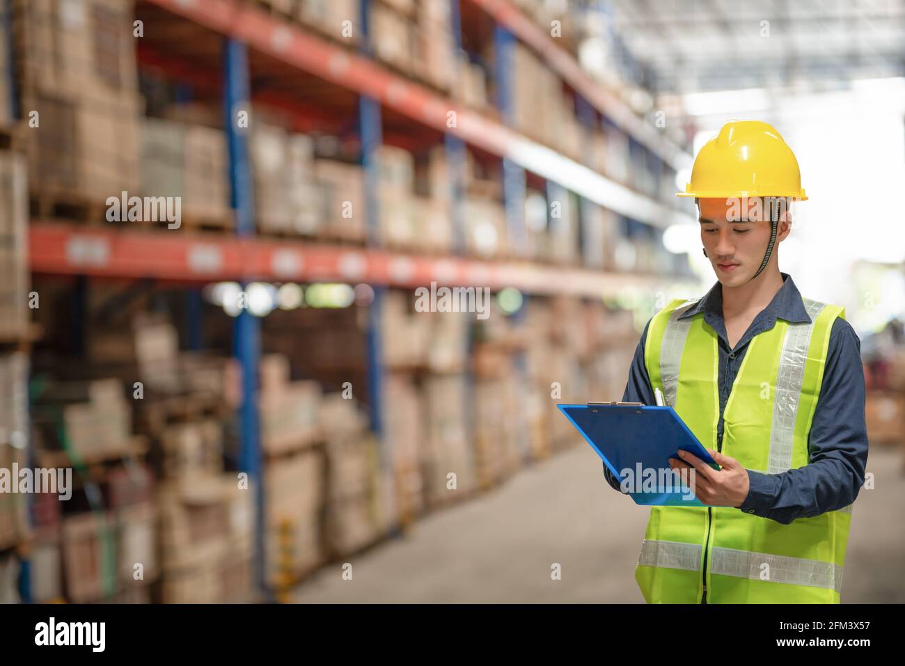 Addetto al magazzino che controlla le confezioni su scaffale in un grande negozio Foto Stock