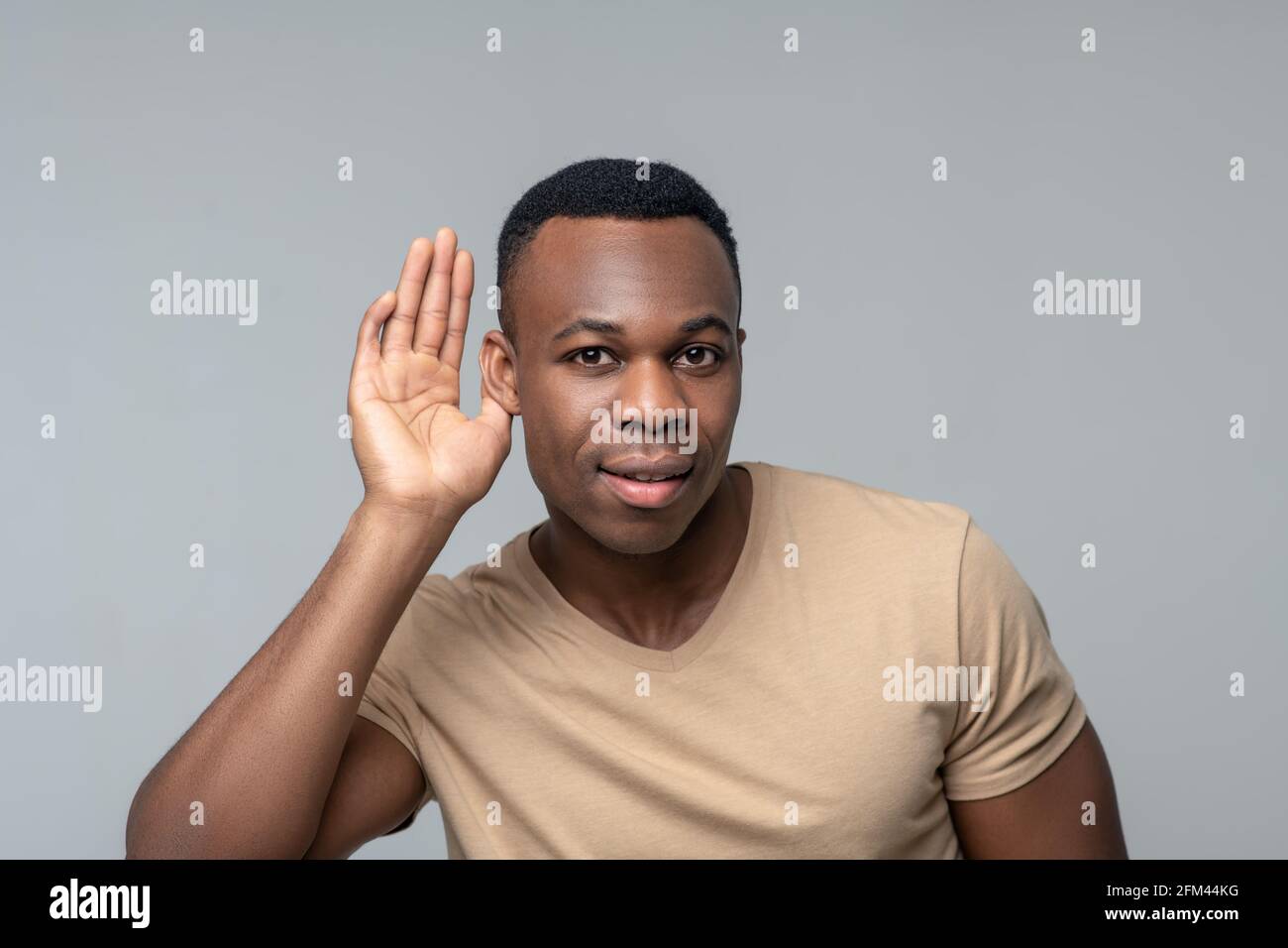 Uomo preoccupato di ascoltare con palmo vicino all'orecchio Foto Stock