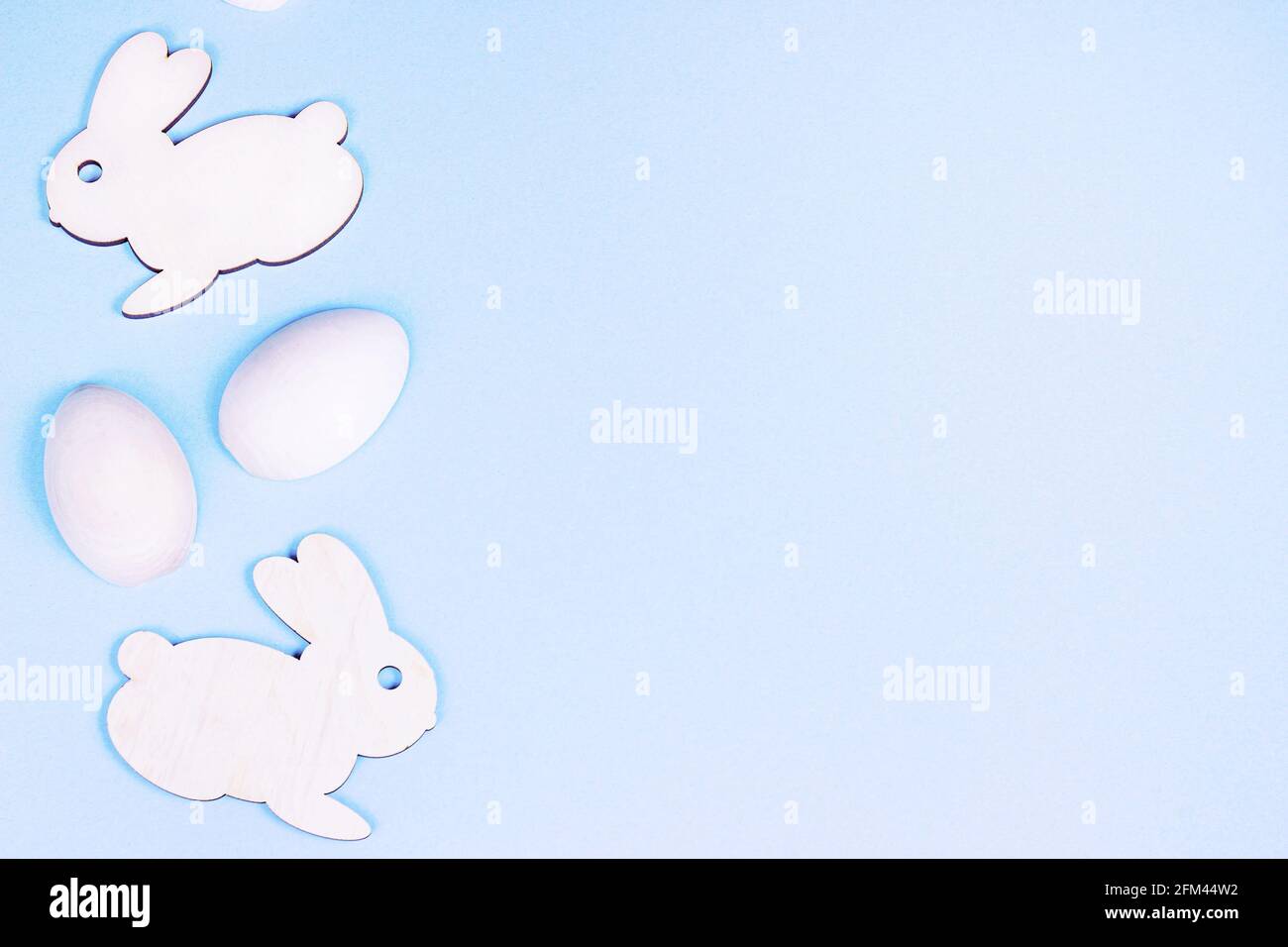 Vista dall'alto piatto Lay divertente coniglietto pasquale in legno con uova come simboli di una vacanza con spazio copia su sfondo rosa chiaro. Foto Stock