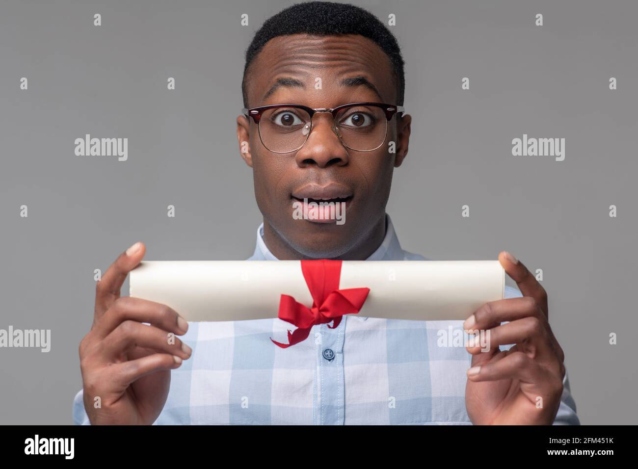 Gioioso uomo che mostra carta legata al nastro Foto Stock