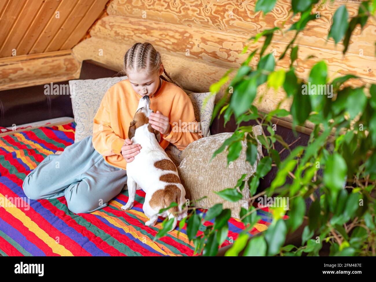 Una ragazza abbracca e bacia un piccolo cane in un accogliente interno di una casa di campagna. Foto Stock